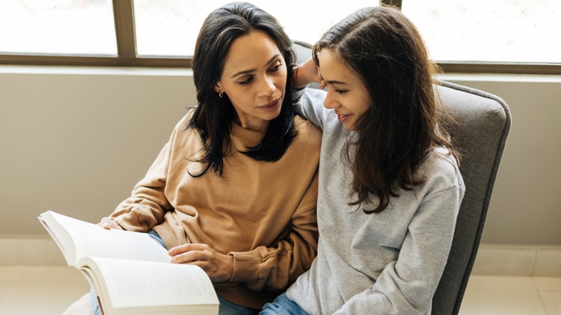Mother and daughter looking at textbook together