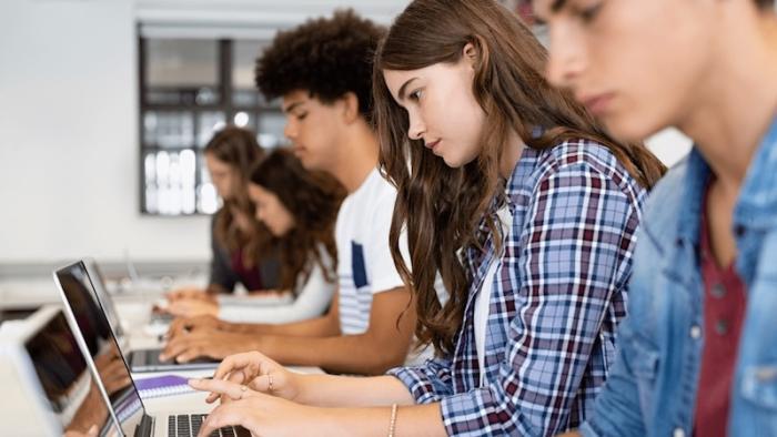 Students focusing on laptops in a classroom setting.