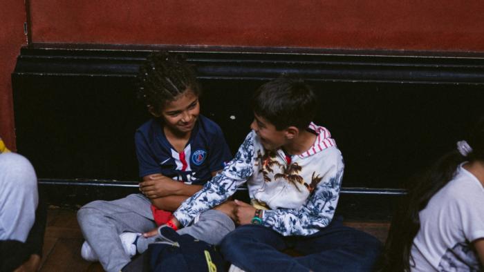 his is a photo of two kids sitting on a bench and chatting.