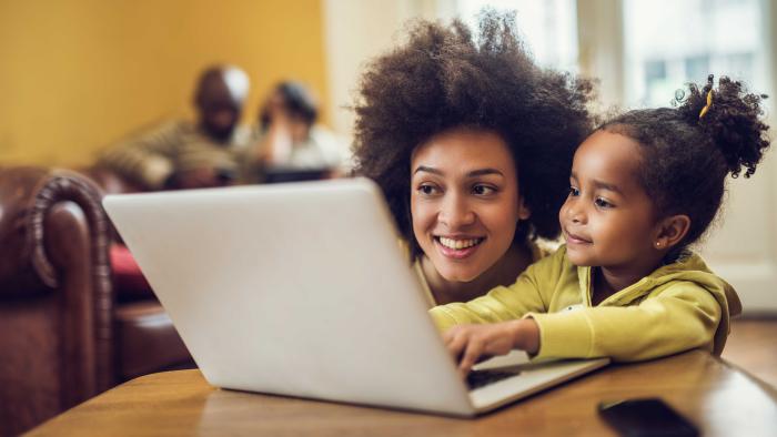 A mother and preschool-aged daughter use a computer together.