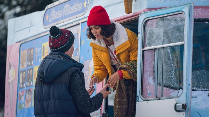 Your Christmas or Mine?: A young biracial woman leans out of an ice cream van talking to a White man wearing a bobble hat.