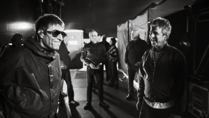 Oasis—Don't Look Back in Anger: Liam and Noel Gallagher, smiling, indoors, black and white photo