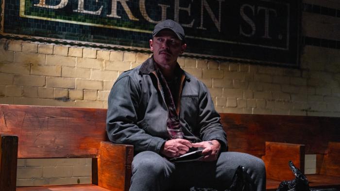 5lbs of Pressure Movie: Adam DeSalvo (Luke Evans) sits on a bench in a train station, holding a sketch pad in his lap