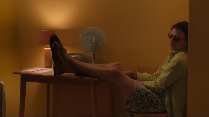 Urchin: A young White man wearing sunglasses with his feet up on a table while sitting inside