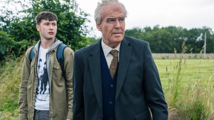 The Last Rifleman Movie: Pierce Brosnan as a World War II veteran and a younger White male stand in a grassy field.