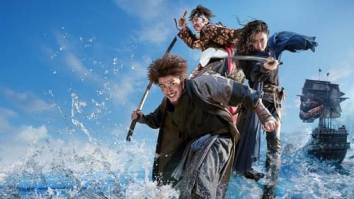 Three pirates rush on shore with swords drawn.