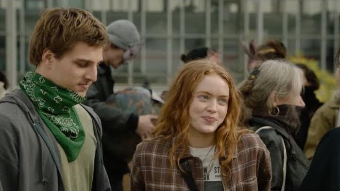 A Sacrifice: Sadie Sink smiles at a person out of shot, as Jonas Dassler looks on