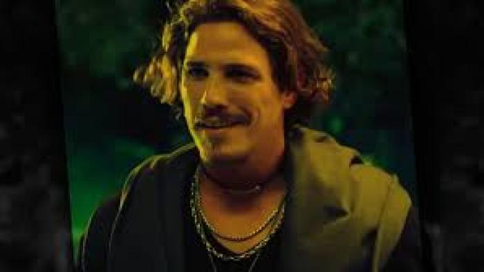 A Vampire in the Family movie: A Brazilian man with mustache and necklaces smiles in a doorway