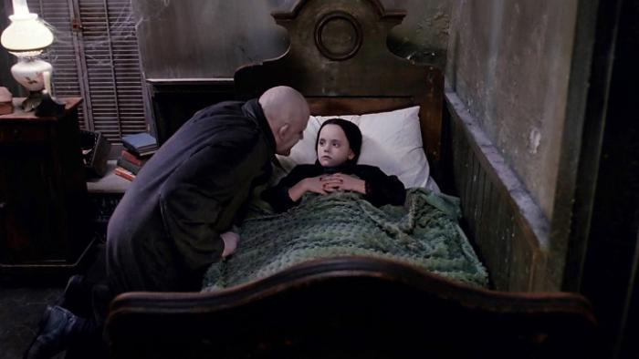 The Addams Family Movie: A character hunches over Wednesday's bed, speaking with her