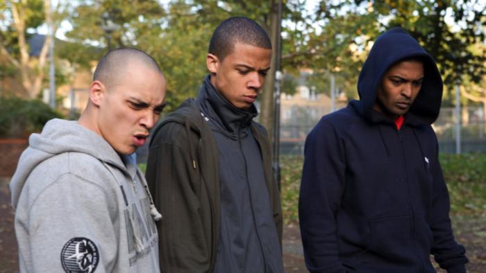 Adulthood: Three young men standing outdoors with serious expressions