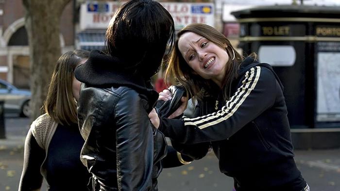Adulthood: Two young women arguing in a street, one pulling the other's hair as another woman looks on