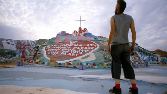 Adventures of the Naked Umbrella Movie: Sam (Jeremy Davies) stands with his back to us, gazing at the plaster "Salvation Mountain"