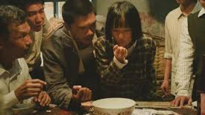 A Foggy Tale: Group gathered around a table, focused on a bowl and money, intense expressions.