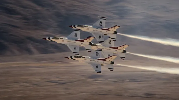 Air Force Elite: Thunderbirds movie: 4 F-16 jets fly close together in diamond formation, desert and mountains in background
