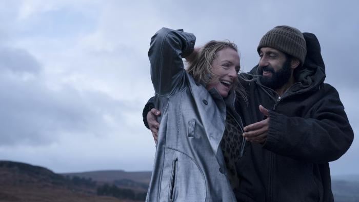 Ava & Ali: Adeel Akhtar and Claire Rushbrook stand together talking in a field wearing waterproofs.