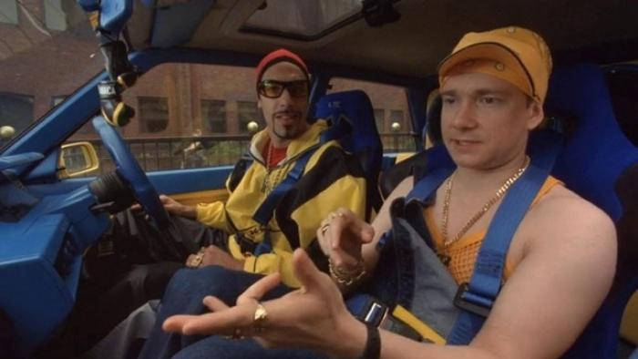 Ali G InDaHouse Movie: Two men in a car, casually dressed, discussing and gesturing