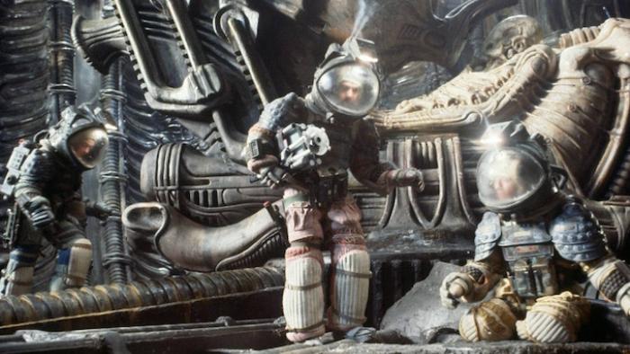 Alien Movie: Three astronauts wearing bubble-head suits stand in front of giant machinery