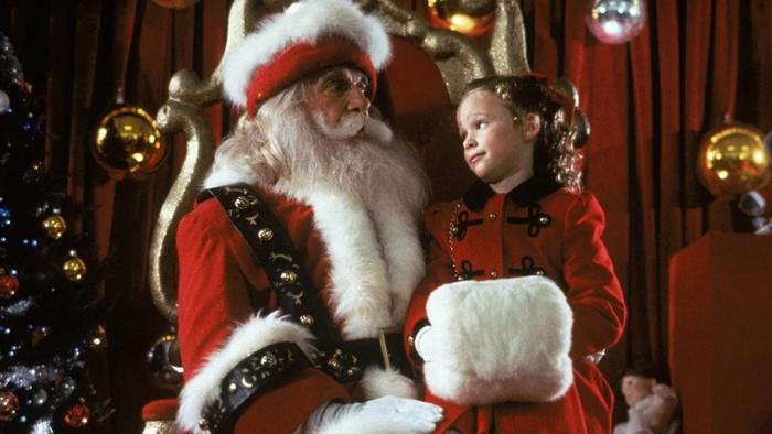 All I Want for Christmas movie: A young girl wears a red outfit as she sits on the lap of Santa