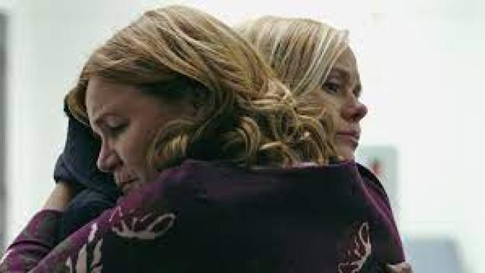 Two sad women hug.