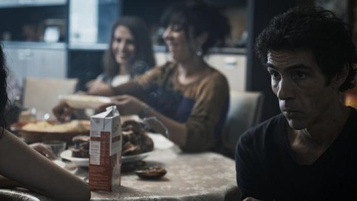 Alpha: A man looks serious while sat at a family gathering
