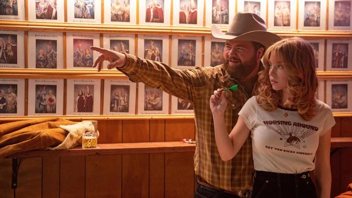 Americana movie: Sydney Sweeney stands in front of Paul Walter Hauser, about to throw a dart at a bar