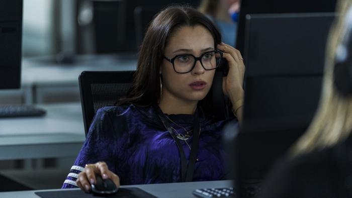 American Sweatshop Movie: Ava, at her desk, reacts to something shocking on her computer screen