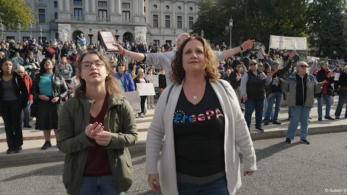 An American Pastoral movie: Tina Wilson and friend stands in front smiling at a pro-life rally