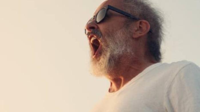 Andre is an Idiot: Elderly man in sunglasses shouting under a bright sky.