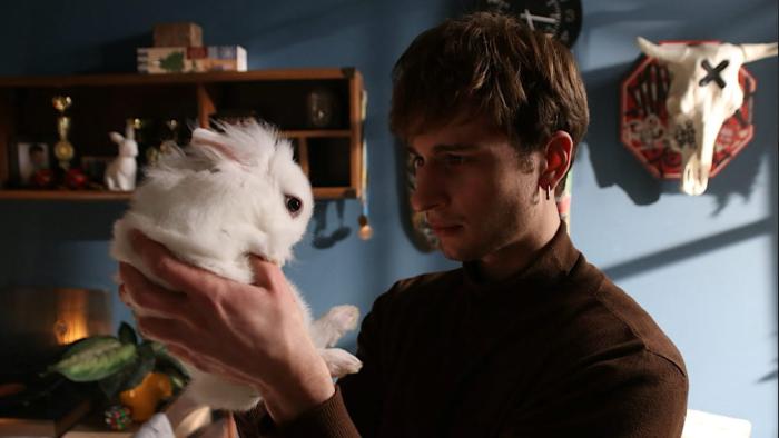 Animals in War: a young man holds up a white bunny in his hands