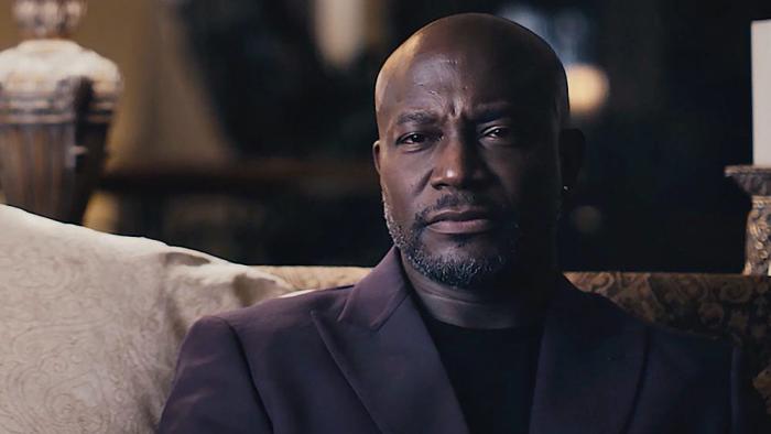 Another Man’s Wife movie: Taye Diggs sits on a couch wearing a suit