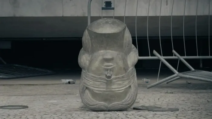 Apocalypse in the Tropics movie: Toppled statue head turned upside down lies on the ground after people stormed the government building