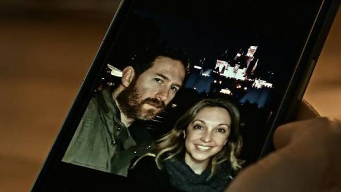 A Toxic Love Story: A couple smiles in a smartphone photo, city lights in the background.