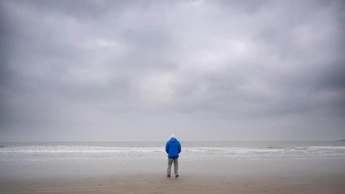 Ocean with David Attenborough: Sir David Attenborough wears a blue jacket and stands looking out at the ocean, a gray, cloudy sky above