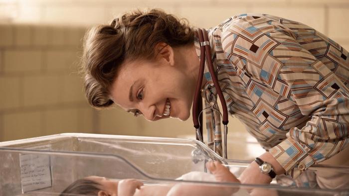 Audrey's Children movie: Natalie Dormer smiles and leans down over a baby in a hospital infant crib