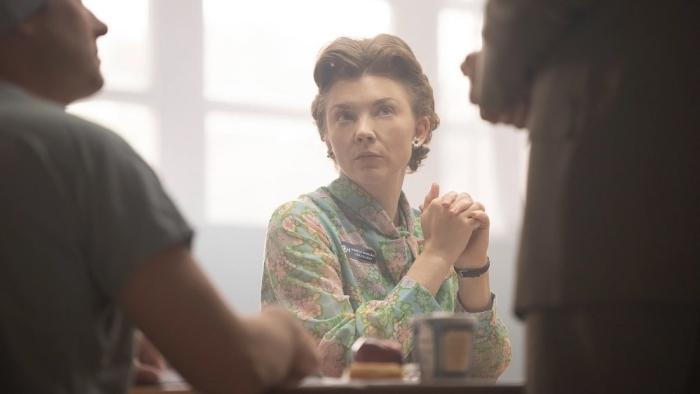 Audrey's Children movie: Natalie Dormer sits at a conference table, hands clasped, looking up at a person standing