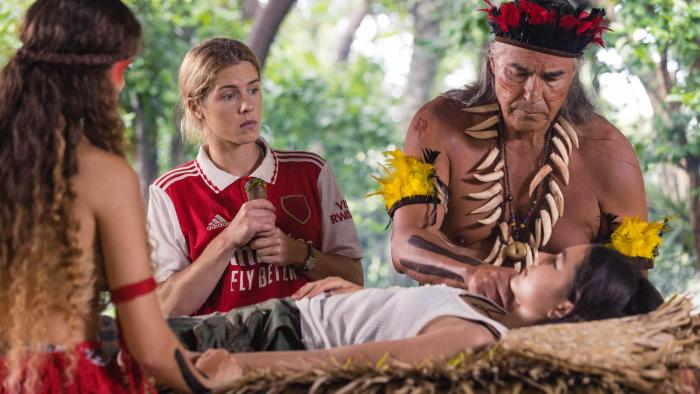 Autumn and the Black Jaguar movie: A blonde White woman looks on as an Indigenous elder treats a female patient in the jungle