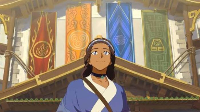 Avatar Aang The Last Airbender Movie: Katara smiles in front of a building carrying colorful banners representing the four different elements..