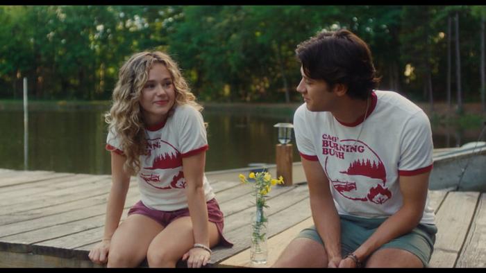 Bad Counselors movie: Two characters in camp shirts sit on a dock