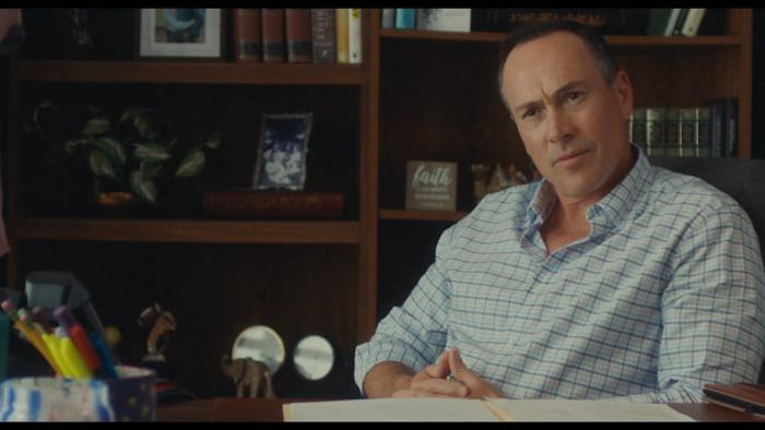Bad Counselors movie: Chris Klein sits at a desk with his hands folded together