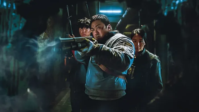 Badland Hunters movie: Korean man with shotgun center, points the way forward while being flanked by Korean man and woman