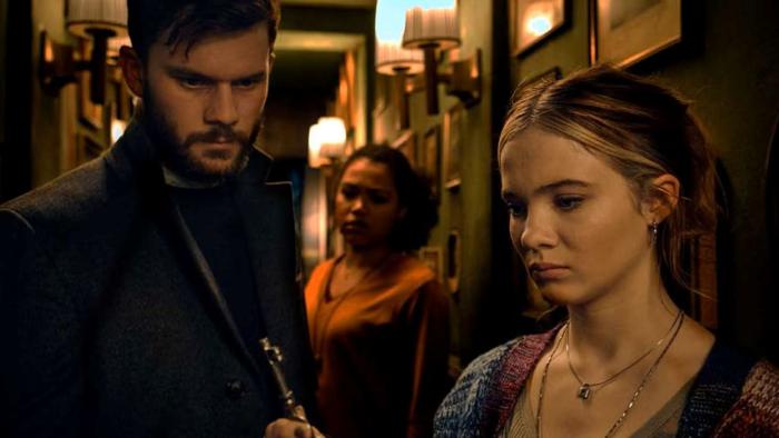 Baghead: Two young women and a man stand in a dimly-lit hallway, looking tense and focused