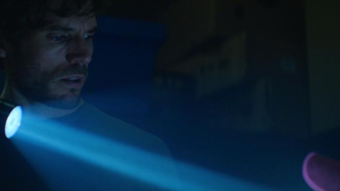 Bagman Movie: Holding a flashlight, Pat (Sam Claflin) spies something curious in the dark