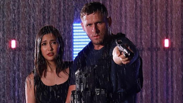 Bang 2025 movie: Jack Kesy stands next to Marie Broenner in the rain while pointing his gun