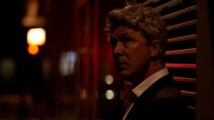 Barber: Aidan Gillen looks up, a dimly lit street scene behind him