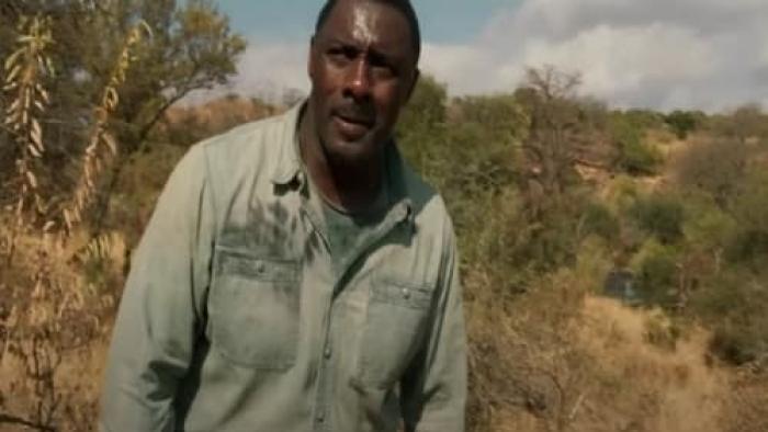 Beast Movie: A man looks out into the distance while standing in an African savanna