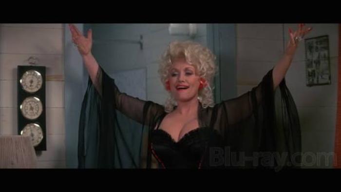  The Best Little Whorehouse in Texas: Dolly Parton with open arms, wearing a sheer black robe, smiling.