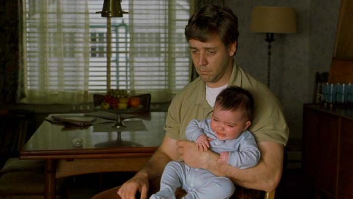 A Beautiful Mind movie: A depressed looking Nash holds a crying baby in a dark room