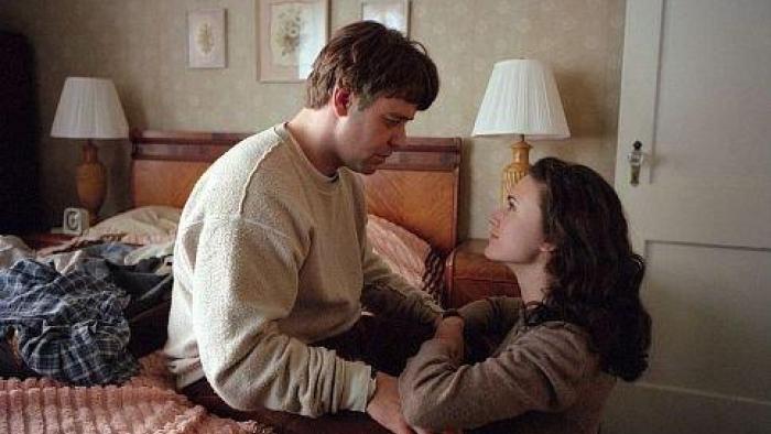 A Beautiful Mind movie: Nash sits on the bed dejectedly, Alicia kneeling on the ground smiling as they look at each other