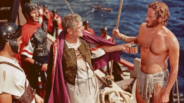 Ben Hur movie: Shirtless man offers a cup to a robed Roman official on a ship