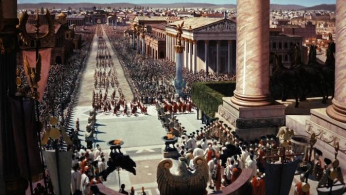 Ben Hur movie: Roman soldiers march in formation through a grand ancient city with temples and columns visible